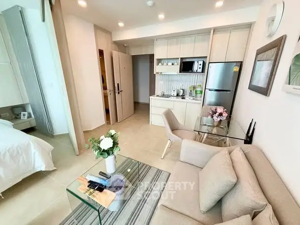Modern studio apartment with open kitchen and cozy living area, featuring elegant decor and natural light.