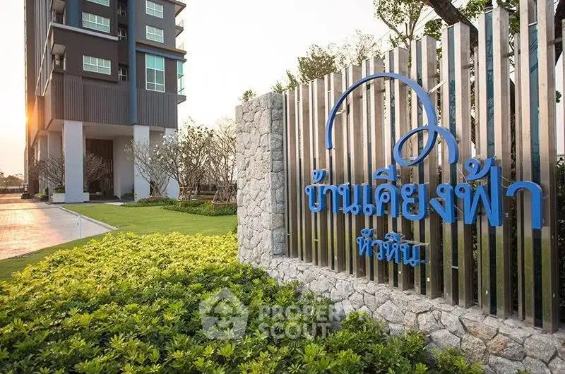 Modern condominium exterior with lush landscaping and stylish signage at sunset.