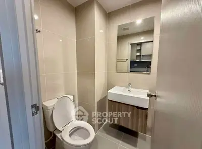 Modern bathroom with sleek fixtures and neutral tiles, featuring a wall-mounted sink and toilet.