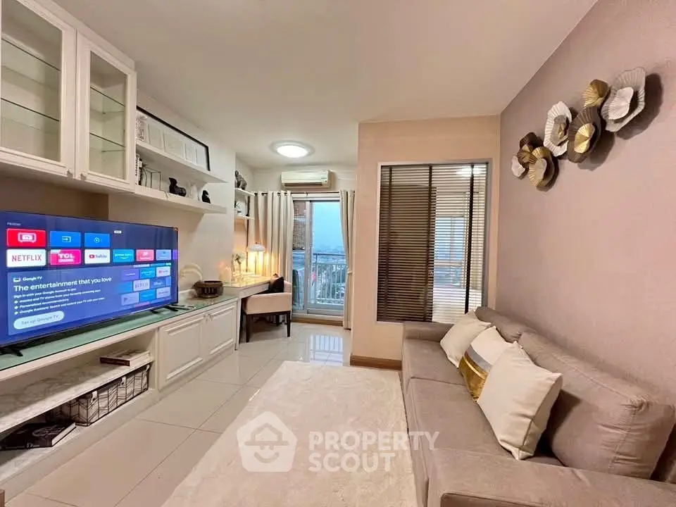 Modern living room with stylish decor and large TV, featuring a cozy seating area and balcony view.