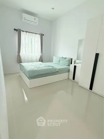 Spacious bedroom with modern furnishings and natural light, perfect for relaxation and comfort.