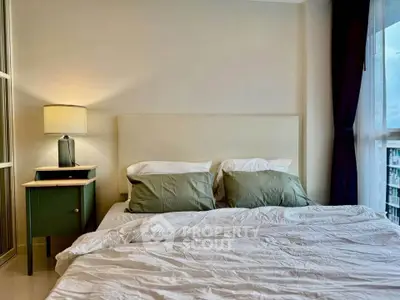 Cozy bedroom with stylish decor and large window offering natural light and city view.