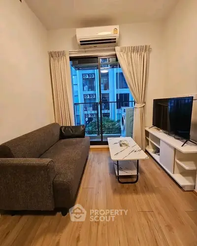 Cozy living room with modern sofa, TV, and balcony view in stylish apartment.