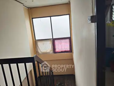 Cozy stairwell with natural light and wooden railing in a residential property.