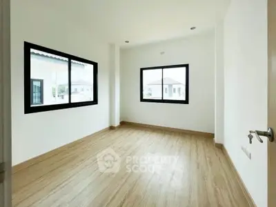 Spacious empty room with large windows and wooden flooring in modern home