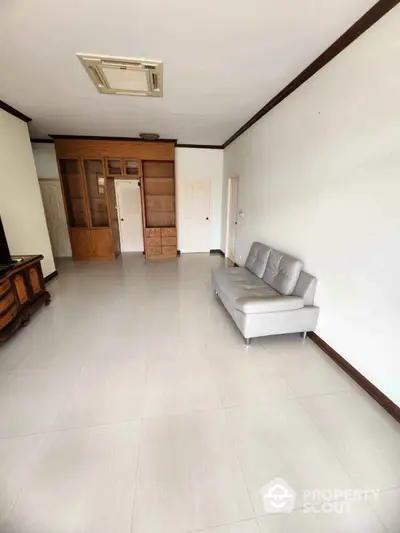 Spacious living room with modern sofa and built-in wooden cabinets, perfect for stylish living.