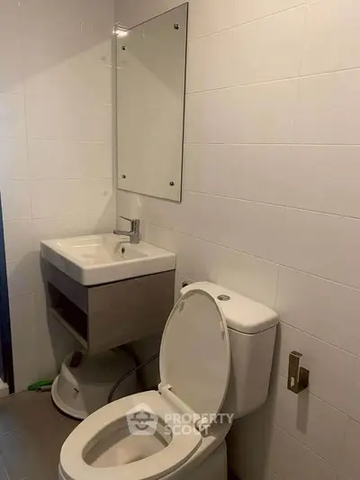 Modern bathroom with sleek fixtures and minimalist design, featuring a wall-mounted sink and toilet.