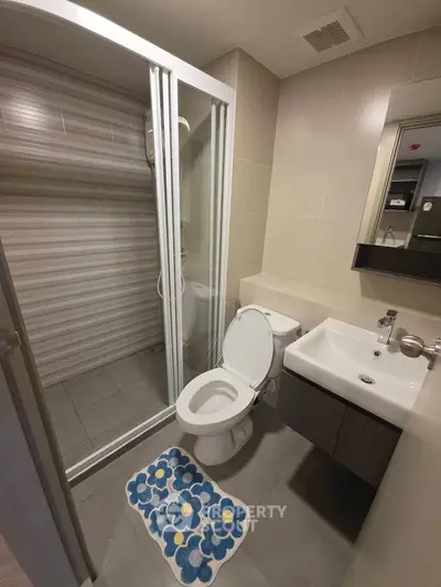 Modern bathroom with glass shower, sleek sink, and toilet in a contemporary apartment.