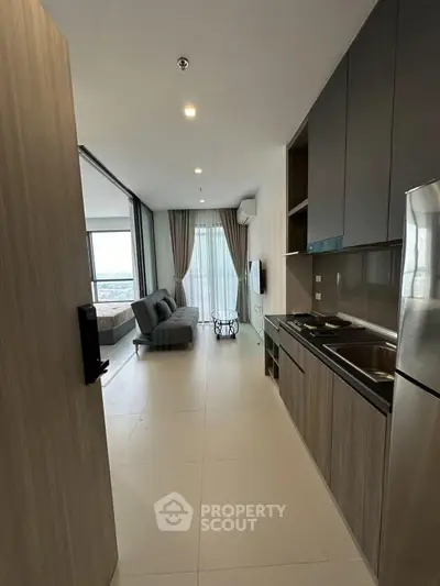 Modern open-layout kitchen and living room with sleek design and large windows offering natural light.