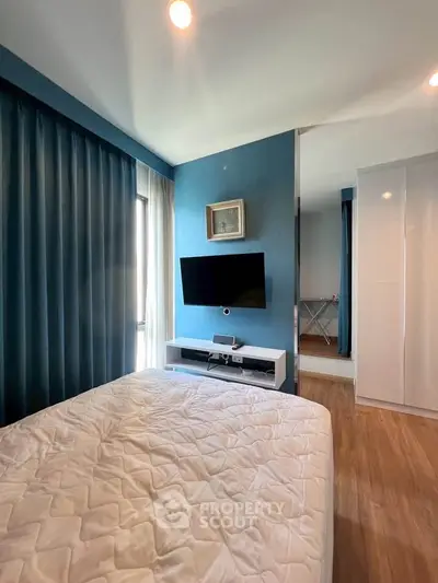 Modern bedroom with blue accents, wall-mounted TV, and sleek storage solutions.