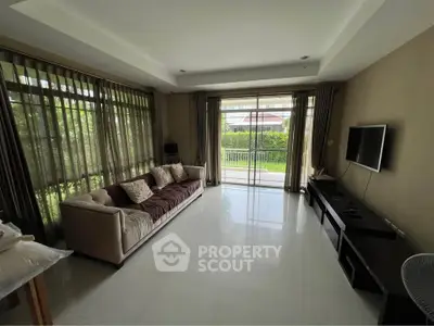 Spacious living room with large windows and garden view, perfect for relaxation and entertainment.