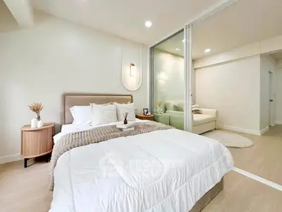 Modern bedroom with cozy decor and adjoining living area in a stylish apartment.