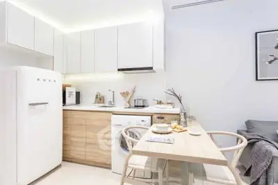 Modern kitchen with sleek white cabinets and integrated appliances in cozy apartment.