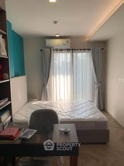 Modern bedroom with natural light, featuring a bed, desk, and large window with curtains.