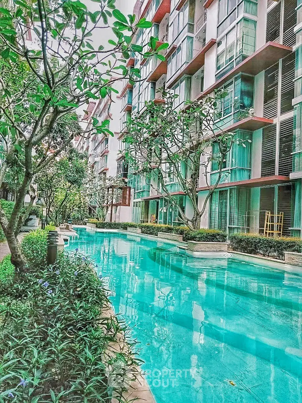 Luxurious residential building with serene pool and lush greenery, perfect for relaxation and modern living.