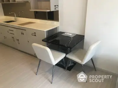 Modern kitchen with sleek black dining table and two chairs, featuring a minimalist design and ample counter space.