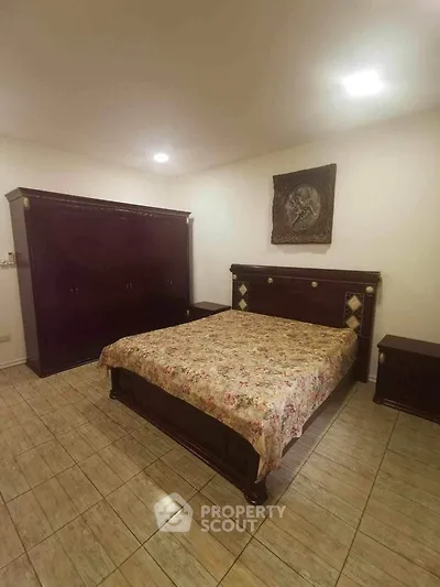 Spacious bedroom with classic wooden furniture set and tiled flooring, offering a comfortable and timeless living space.