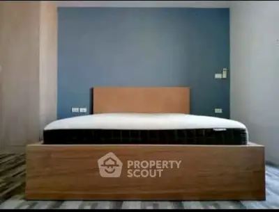 Modern minimalist bedroom with wooden bed frame and blue accent wall