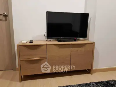 Modern living room with sleek wooden TV stand and flat-screen television.