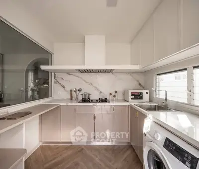 Modern kitchen with sleek cabinetry, marble backsplash, and integrated appliances in a bright, airy space.