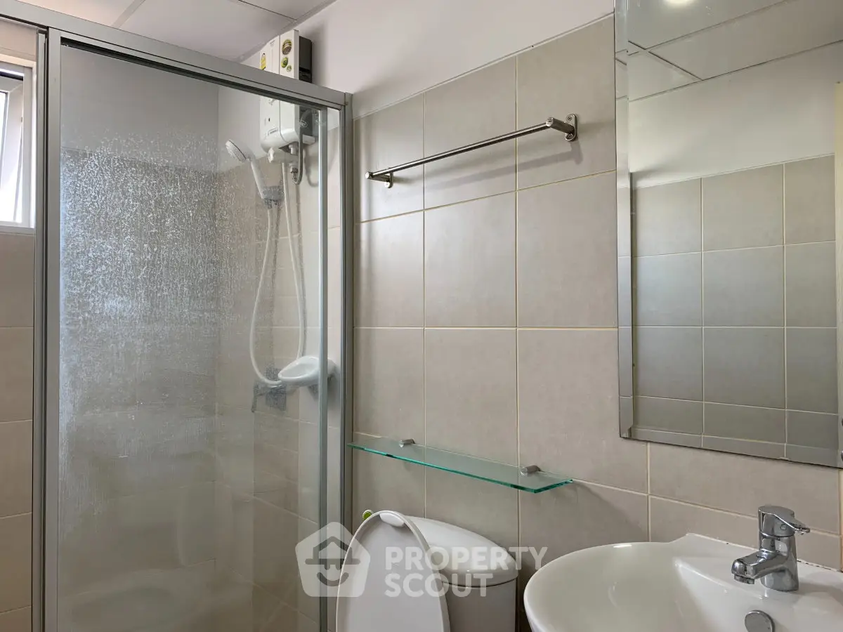 Modern bathroom with glass shower enclosure and sleek fixtures in a contemporary apartment.