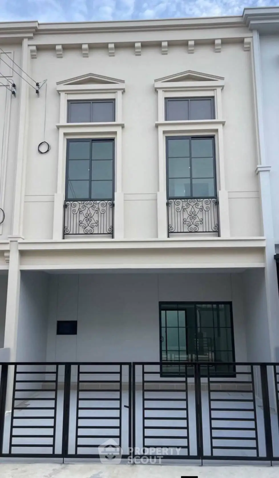 Elegant modern townhouse exterior with stylish balcony railings and gated entrance, perfect for urban living.