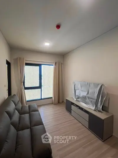 Modern living room with sleek furniture and large window, perfect for cozy relaxation.