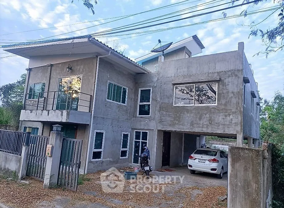 Modern concrete house with carport and balcony in suburban setting