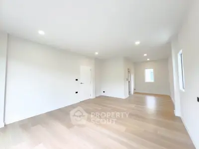 Spacious empty room with wooden flooring and white walls, ideal for customization.