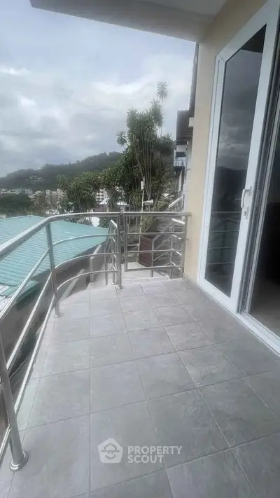Spacious balcony with scenic view and modern railing in a high-rise apartment.