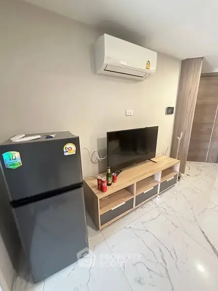 Modern living room with sleek TV stand, air conditioning, and compact fridge on glossy marble floor.