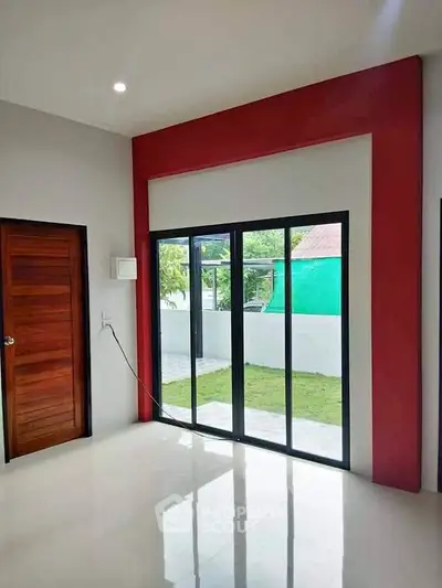 Modern interior with sliding glass doors leading to a garden, featuring sleek design and natural light.