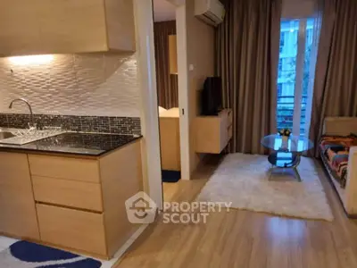 Modern open-layout living room with kitchen, featuring wooden flooring and stylish decor.