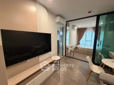 Modern living room with TV and view into bedroom through glass partition