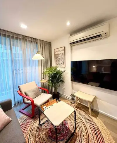 Cozy living room with modern decor, featuring a large TV, stylish furniture, and natural light.