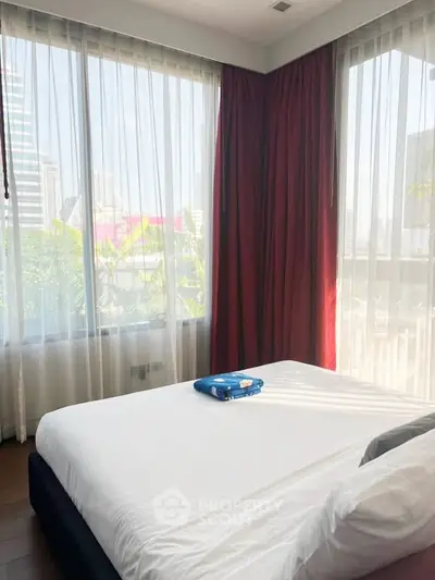 Spacious bedroom with large windows offering city views and natural light.