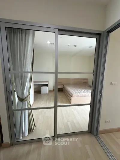 Modern bedroom with sliding glass doors and wooden flooring in a stylish apartment.