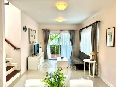 Spacious living room with modern decor and large windows opening to a lush garden view.