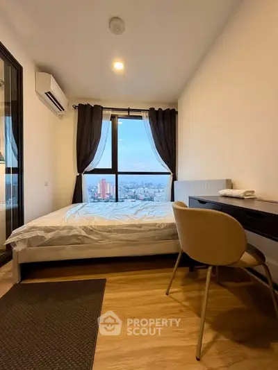 Modern bedroom with city view, featuring a cozy bed, desk, and large window with curtains.