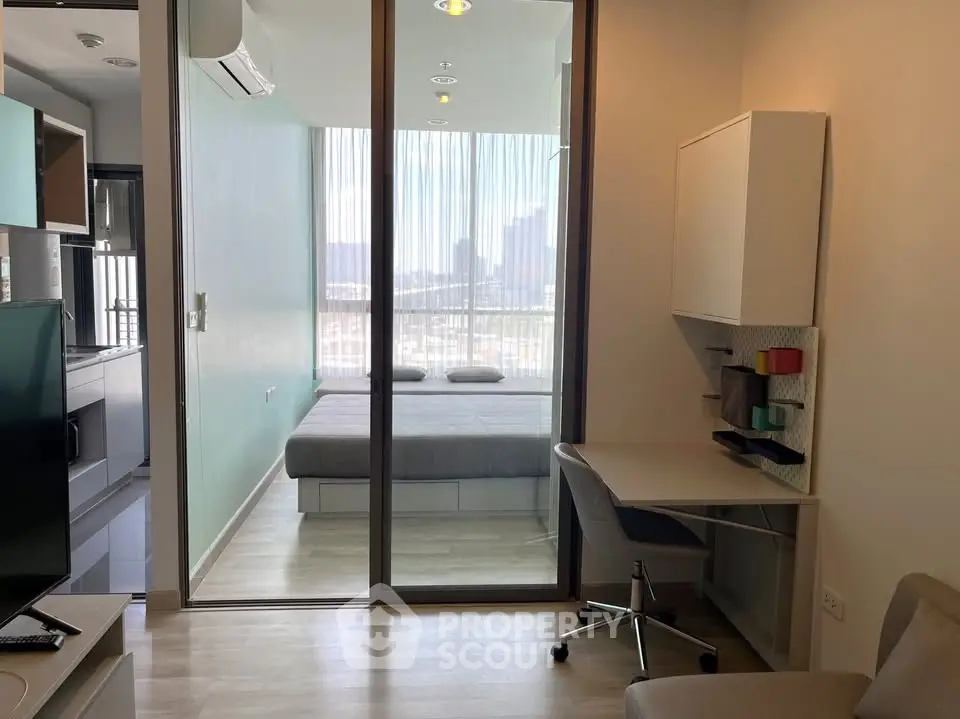 Modern studio apartment with glass partition, stylish workspace, and city view.