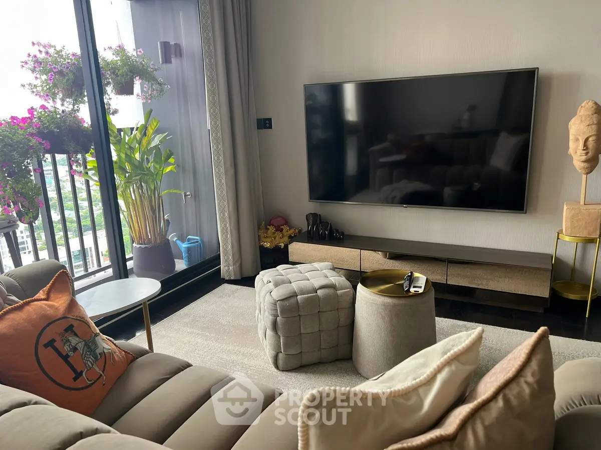 Modern living room with large TV and balcony view, featuring stylish decor and comfortable seating.