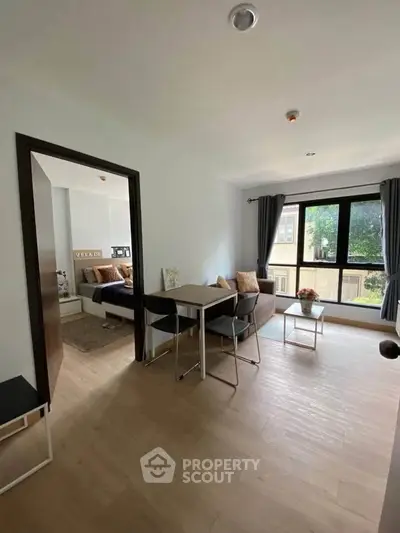 Modern living room with dining area and large window offering natural light.