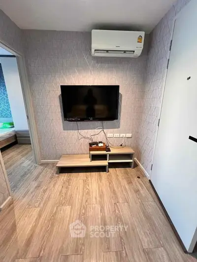 Modern living room with wall-mounted TV and air conditioning in stylish apartment.