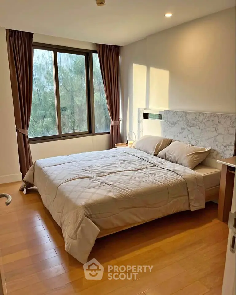 Cozy bedroom with large window and elegant decor, perfect for relaxation and comfort.