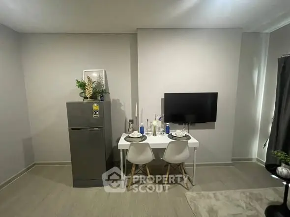Modern dining area with compact fridge and wall-mounted TV in minimalist apartment.