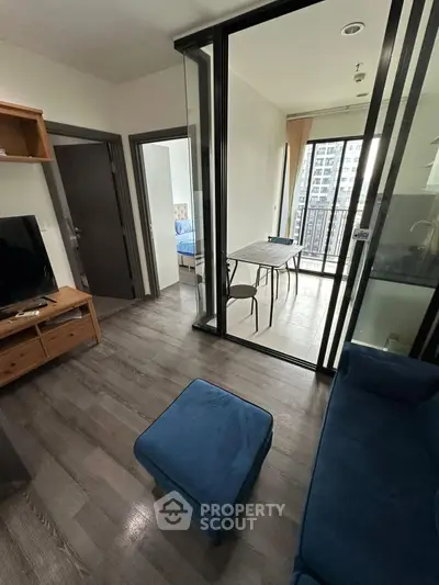 Modern living room with glass partition and balcony view in urban apartment.