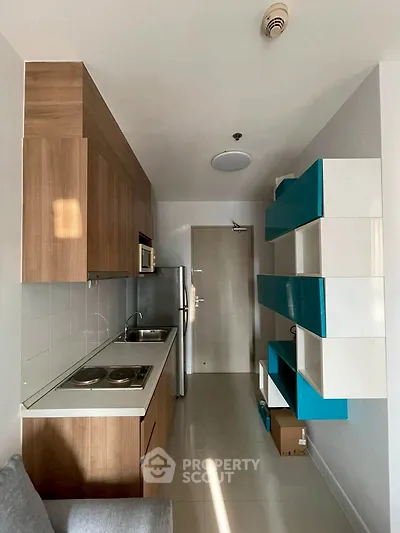Modern compact kitchen with sleek cabinetry and stainless steel appliances in a cozy apartment.