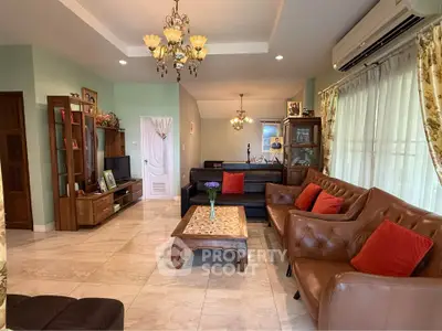 Spacious living room with elegant decor and natural light, featuring leather sofas and a classic chandelier.