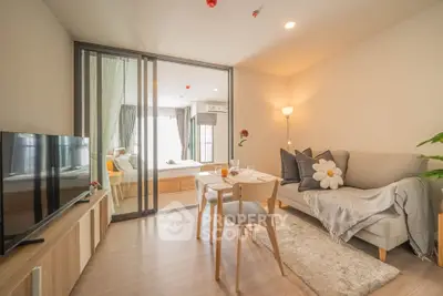 Modern living room with cozy decor and sliding glass doors leading to a bright bedroom.