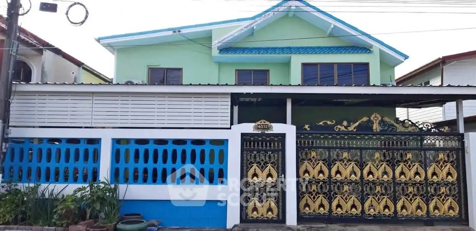 Charming two-story house with ornate gate and vibrant exterior colors.